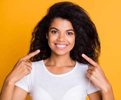 Happy young woman pointing at her smile